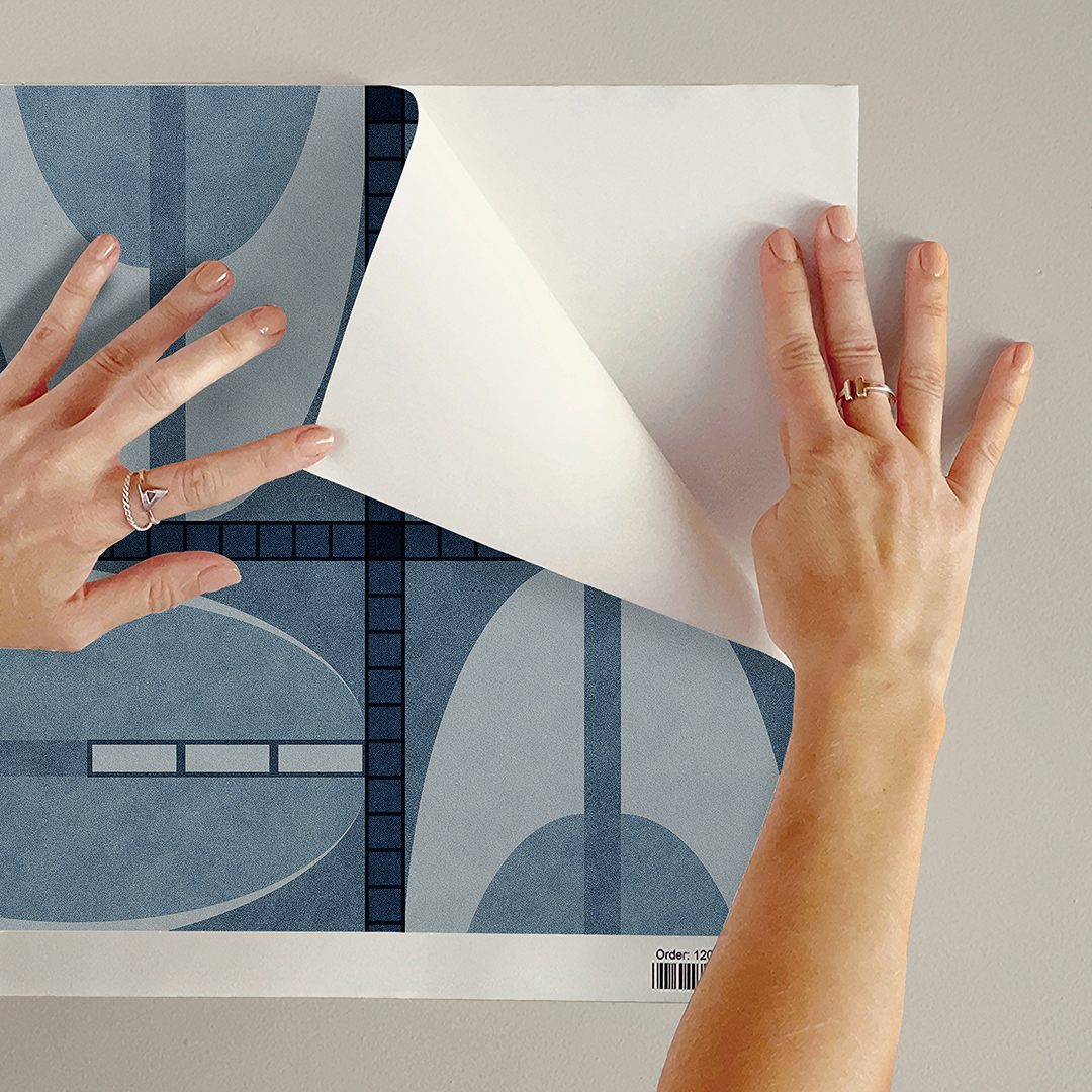 The artwork features a repeating geometric pattern of symmetrical shapes resembling elongated, curved diamonds or petals in various shades of blue and green. Each shape is split vertically with one half filled with a light blue and the other half filled with green or darker blue. The background is a light, almost pastel blue, which provides a soft yet vibrant backdrop. One of the blue shapes near the upper left contains a white starburst element, adding a focal point of brightness to the composition. The overall design conveys a modern, mid-century aesthetic with clean lines and harmonious color contrasts.